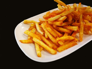 French fries in white plate on black table