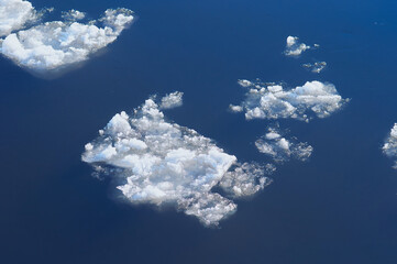 Ice floes float on the river. Seasonal ice drift. Reflection of the blue sky in the water. Natural...