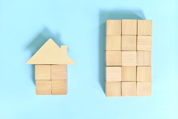 Buy condominium unit  versus house and lot concept. Wooden blocks building and house model.