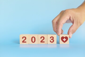 New year 2023 health goal and healthcare priority concept. Wooden blocks on blue background with...