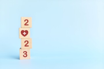 New year 2023 health goal and healthcare priority concept. Wooden blocks on blue background with icon.