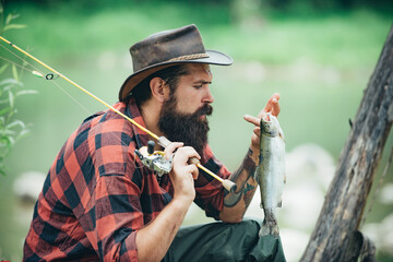 Portrait of young bearded man fishing at a lake or river. Flyfishing. Fishing hobby and spring...
