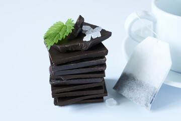 Bitter chocolate with salt and mint leaf on a white background. The concept is a tea break.