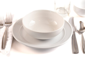 A Table Set with a Clean and Emtpy White Set of Dishes and Silverware Isolated on a White Background