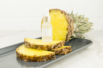 a brightening serum with pineapple extract in a cosmetic white bottle with a pipette stands onpineapple slices. natural cosmetics. Unbranded mock-up.