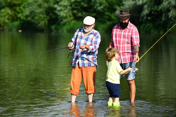 Anglers. Fly fishing for trout. Father teaching son how to fly-fish in river. Grandfather and...