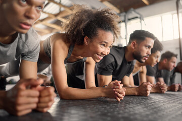 Fitness, woman and plank exercise in group training gym for wellness, healthy lifestyle and workout. Strong, young and happy black girl, athlete and floor push up with friends for sports challenge