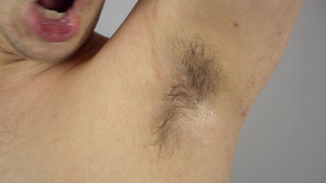 The man sniffs his sweaty armpits. A young man with long hair in his armpits. Like the smell.