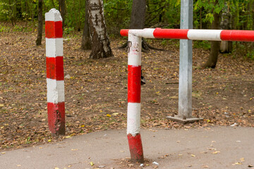 Fototapeta na wymiar An iron barrier in a forest, painted in red and white stripes, a checkpoint.