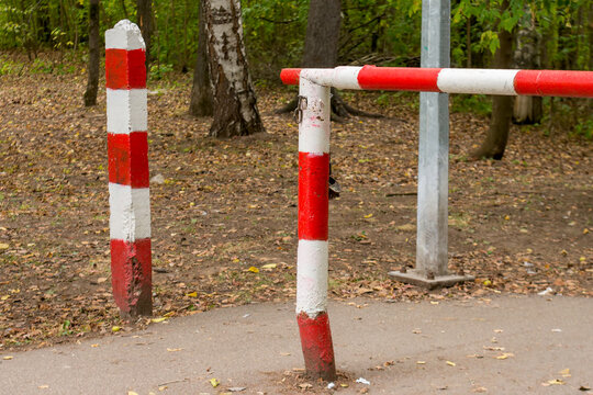 An iron barrier in a forest, painted in red and white stripes, a checkpoint.