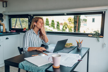 Young woman working at home with laptop and having a video call with family