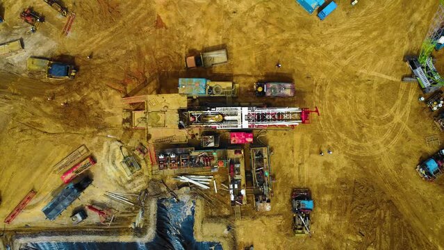 Cinematic Drone Footage of Onshore Drilling Rig equipment structure for oil exploration and exploitation in the middle of jungle surrounded by palm oil trees during sunset and high oil price.