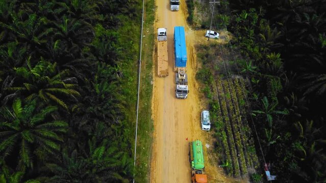 Cinematic Drone Footage of Onshore Drilling Rig equipment structure for oil exploration and exploitation in the middle of jungle surrounded by palm oil trees during sunset and high oil price.