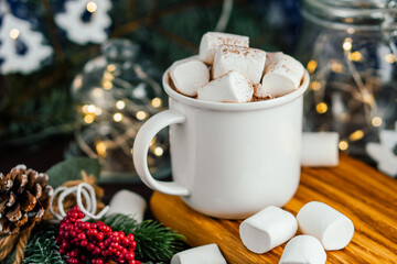 Christmas drink hot chocolate with marshmallows at festive illuminated decoration. Selective focus