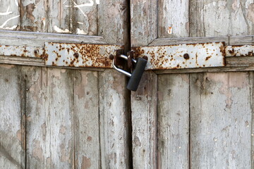 A rusty padlock hangs on a closed gate.