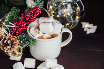 Obraz na płótnie Canvas Christmas drink hot chocolate with marshmallows at festive illuminated decoration. Selective focus