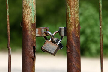 A rusty padlock hangs on a closed gate.
