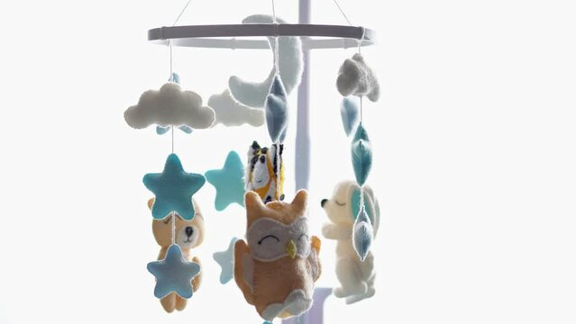 Musical mobile with soft toys for helping baby entertain and sleep in baby crib. Musical mobile toy with plush fluffy animals turns hanging over cot to calm child