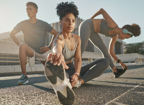 Fitness, Team And Friends Stretching In City Street For Exercise Run, Marathon Training Run Or Cardio Performance Workout. Health Commitment, Focus And Black People Warm Up While Listening To Music