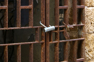A rusty padlock hangs on a closed gate.