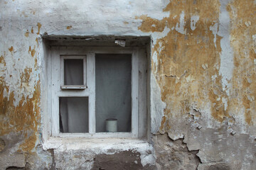 Old window of an abandoned house. Old facade painted in pastel colors.