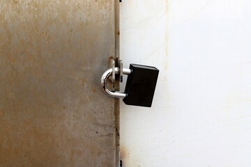 A rusty padlock hangs on a closed gate.