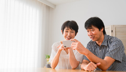 スマートフォンで動画を視聴するミドル男性とミドル女性