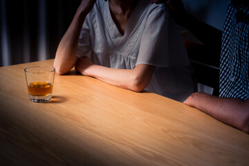 家でうなだれるミドル女性と彼を慰めるミドル男性