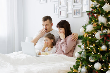 christmas, family and love concept - family watching movie near christmas tree