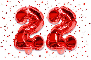 The number of the balloon made of red foil, the number twenty two on a white background with sequins. Birthday greeting card with inscription 22. Numerical digit, Celebration event.
