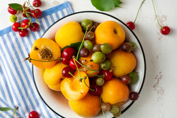 Obraz na płótnie Canvas Summer fruits in white bowl pie concept cherry apricots berry top view