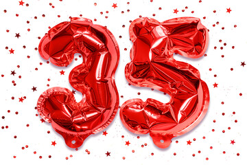 The number of the balloon made of red foil, the number thirty five on a white background with sequins. Birthday greeting card with inscription 35. Anniversary concept.