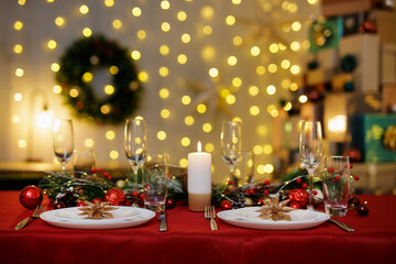 Beautiful table with plates and champagne glasses for christmas dinner. Garland on background