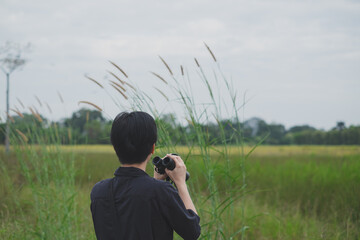 A bird watcher is using a binoculars to search bird in the field. Concept of bird watching,...