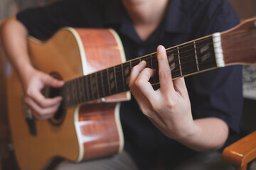A close up of musician playing an acoustic guitar for entertainment or practicing for perfomance....
