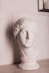 Plaster head of the statue against the background of a white brick wall