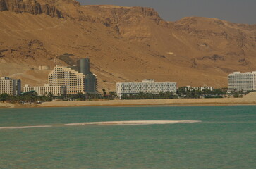 Landscape of the Dead Sea, turquoise water and salt mushrooms, against the backdrop of a terracotta...