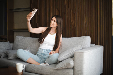 Young brunette european girl blogger speaking on the phone ringing using smartphone in a modern...