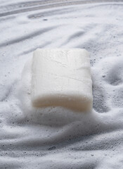 Solid soap placed against a background of foam.