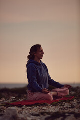 Woman practicing yoga outdoors in sunset sunrise time.