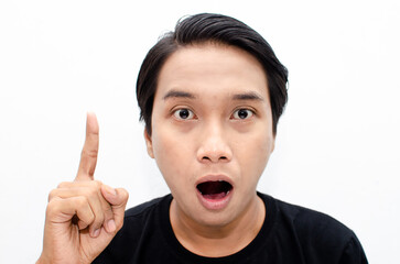 headshot of shocked, surprised, amazed young asian man in black tshirt isolated over white pointing with finger best for bussines advertismnet