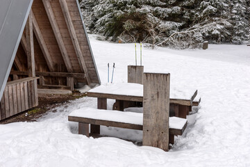 Rest area with wooden hut, bench and table in winter forest