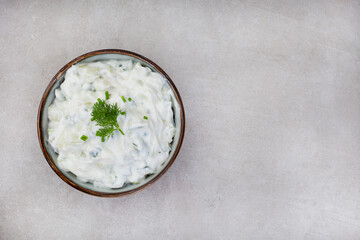 Fresh Greek favorite, Tzatziki made with cucumber, yogurt and herbs. On a mottled grey surface with copy space

