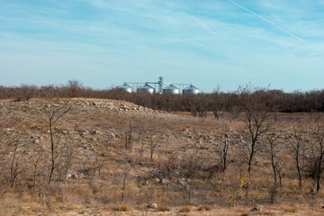 View through the empty field and small desert at the industrial buildings.