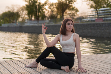 Young woman doing yoga by the lake