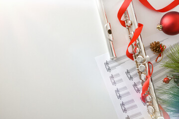 Flute on music sheet with Christmas decoration on white table