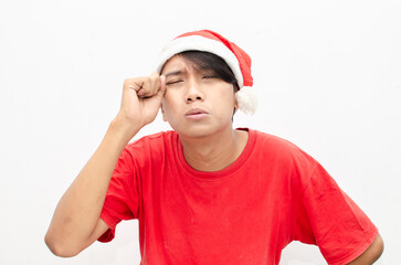 Sad attractive Asian man in red Christmas theme clothes isolated over white. christmas concept man in red santa claus clothes with sad expression wiping the tears.