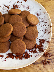 Cacao biscuits in white plate on wooden background