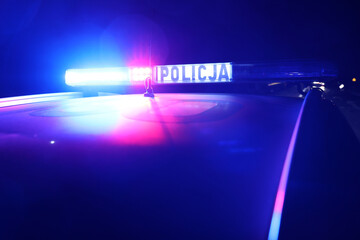 Nocna interwencja alarmowa policji - Sygnalizator błyskowy niebieski na dachu radiowozu policji polskiej w nocy. © FotoDax