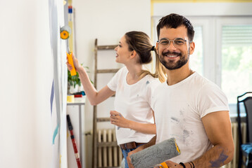 Obraz premium Portrait of smiling young couple painting wall in their home together.